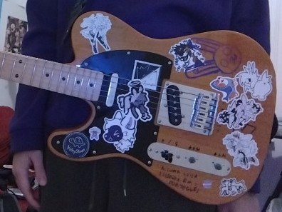 Picture of a Telecaster decorated with stickers and marker scribbles